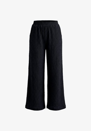 Zwarte wijde broek met gestructureerde stof en elastische tailleband, weergegeven tegen een witte achtergrond.