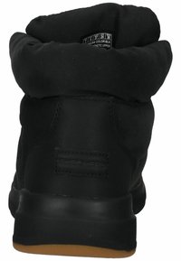 Botte cheville synthétique noire avec un revers, un dessus texturé, une semelle en caoutchouc lisse et un logo à l'arrière.