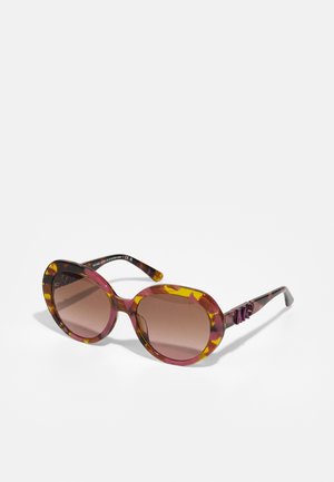 Ochelari de soare ovali cu un cadru din plastic marmorat în nuanțe de roz, galben și negru. Lentilele de culoare maronie și brațele texturate prezintă un accent cu un logo violet.