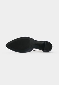 Vue de la semelle d'une chaussure noire à bout pointu avec une semelle texturée et un talon bas, montrant le nom de la marque "Gabor" embossé près de la voûte plantaire.