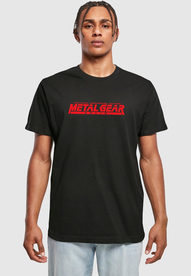 T-shirt en coton noir avec le texte "METAL GEAR SOLID" en rouge et un slogan plus petit. Col rond et manches courtes, avec une coupe décontractée.