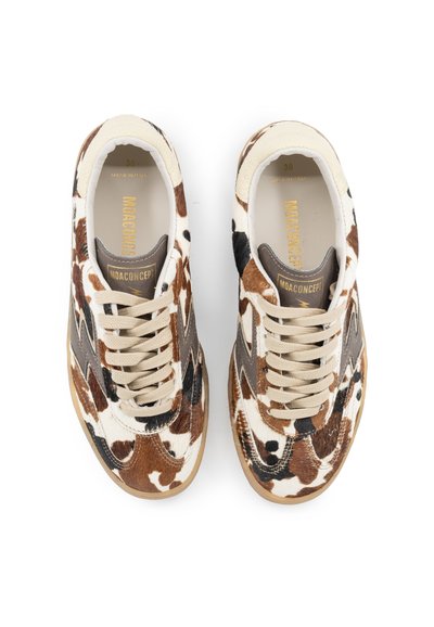 Sneaker marroni e crema con un motivo in pelle di mucca, dotati di lacci beige, accenti in suede e una parte superiore testurizzata. Marchio dorato sulla linguetta.