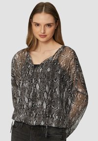 Blouse en imprimé serpent noir et gris, transparente, avec un décolleté en V et des manches amples, dotée de cordons de serrage au bas. Idéale pour le superposition.