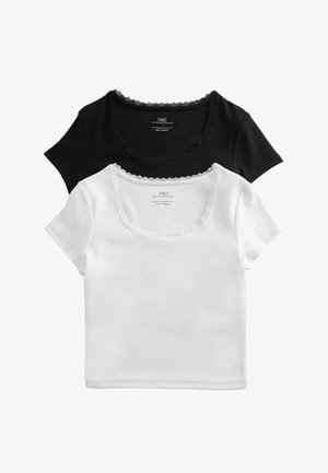 Dwa bawełniane topy z krótkim rękawem, jeden czarny i jeden biały, każdy z falowanym koronkowym wykończeniem wokół okrągłego dekoltu.