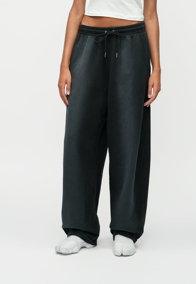 Σκούρο γκρι φαρδιά παντελόνια φόρμας με ελαστική μέση και κορδόνι, διαθέτοντας μαλακή υφή και πλάγιες σχισμές στο στρίφωμα.