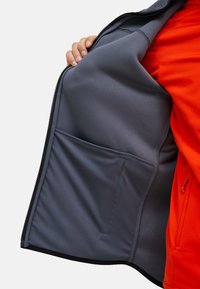 Innenraum einer grauen Fleecejacke mit kontrastierendem, leuchtend orangefarbenem Außenmaterial. Verfügt über eine Tasche auf der linken Seite, eine glatte Textur und einen Reißverschlussverschluss.