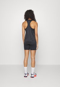 Débardeur de sport noir sans manches et short assorti, conçus pour le mouvement, avec une coupe dos nageur et une texture de tissu lisse.
