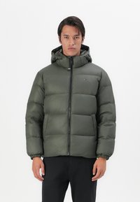 Groene pufferjack met een ritssluiting aan de voorkant, elastische manchetten en een capuchon. Het materiaal heeft een glanzende textuur, met een klein logo op de borst.