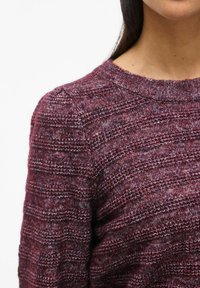 Maglione a maglia bordeaux con scollo rotondo, sottili righe orizzontali e finitura texture su tessuto morbido. Maniche lunghe con dettagli sulle spalle.