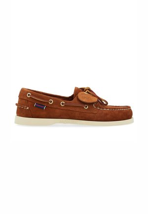 Brown suede moccasin-style shoe with cream rubber sole, lacing detail, and a circular leather tag. Features metal eyelets and contrasting stitching.