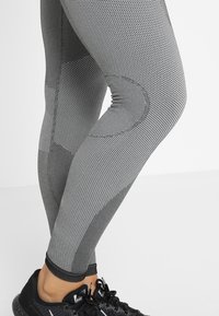 Leggings deportivos gris con un patrón texturizado y un diseño ajustado, que cuentan con acentos oscuros contrastantes y un dobladillo acampanado.
