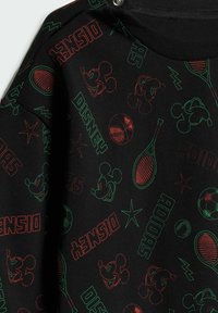 Čierna mikina so živými grafikami Mickey Mouse, športovým vybavením a textom v červenej a zelenej farbe, s okrúhlym výstrihom a cvočkmi.