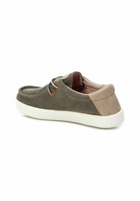 Zapatillas de ante gris con una suela de goma blanca, acento en el talón de gris claro contrastante y cordones decorativos que presentan detalles en rojo y negro.