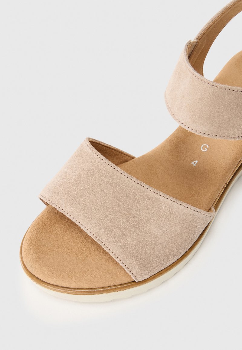 Beige Wildledersandale mit zwei breiten Riemen, flacher Sohle und strukturiertem Fußbett. Schmal zulaufendes Design, minimalistisch und leicht.