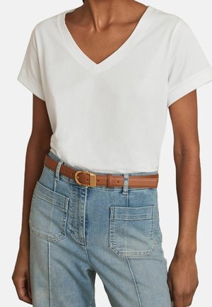 Hvid bomuld t-shirt med v-hals og korte ærmer, kombineret med lyseblå høj talje denim jeans og et brunt læderbælte med guldlås.