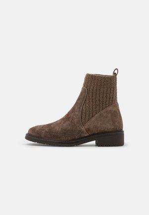 Bottines en daim marron avec col en tricot côtelé, semelle en caoutchouc plate et languette de tirage à l'arrière. Design élégant et texture lisse.
