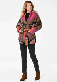 Langer Strickcardigan mit einem Zickzackmuster in Braun, Pink, Orange und Schwarz. Mit einem taillierten Schnitt und großen Taschen. Gemütliche Textur.