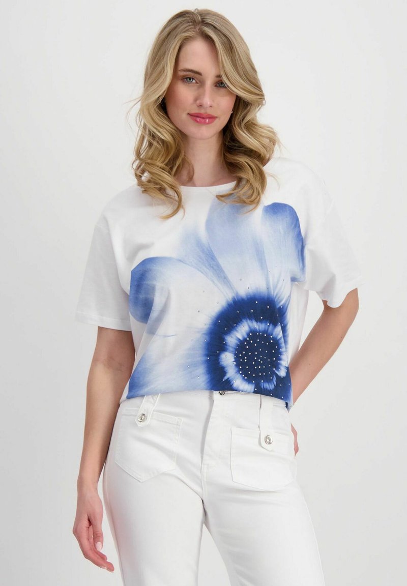 Weißes Kurzarm-T-Shirt mit einem großen blauen Blumendesign und glitzernden Akzenten. Das Shirt hat eine lockere Passform und einen runden Halsausschnitt.
