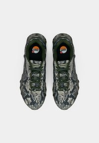 Pár tmavě zelených a šedých tenisek Nike Air Max se vzorem hadí kůže, pohled shora na bílém pozadí.