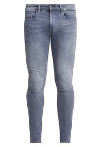 Jeans ajustados en denim azul claro con un acabado deslavado, que cuentan con cinco bolsillos y una cremallera. Textura suave y diseño slim fit.