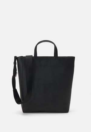 Sac cabas en cuir noir avec poignées courtes et bandoulière ajustable sur fond blanc.