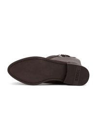 Suela de bota de cuero marrón con textura suave, forma ovalada y costuras sutiles. Cuenta con un tacón texturizado y el nombre de la marca grabado.