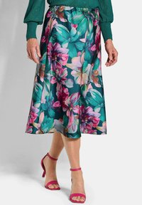 Blumiger Midirock mit türkisfarbenem Hintergrund, der große pinke und grüne Blumen zeigt. Weicher Stoff, ausgestelltes Design, kombiniert mit rosa Riemchenschuhen.