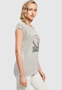 Grå t-skjorte med korte ermer som har et grafisk trykk av en tegneserie-katt og teksten "Tom & Jerry." Mykt bomullsstoff med en avslappet passform.