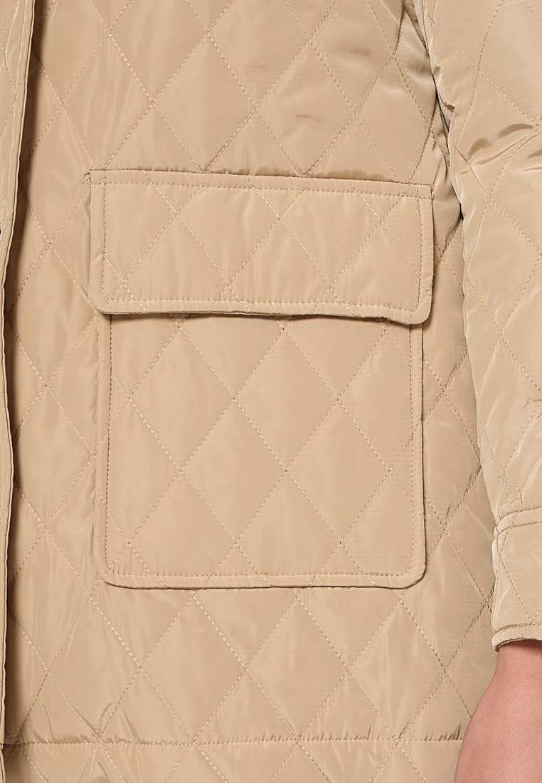 Giubbotto imbottito beige con motivo a diamante, dotato di una grande tasca applicata sul fronte, realizzato in un materiale sintetico liscio.