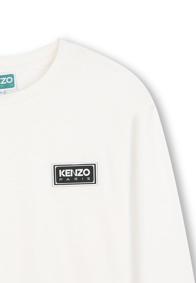 Biała bawełniana koszulka z okrągłym dekoltem, z czarną prostokątną naszywką z napisem "KENZO PARIS" w białym kolorze. Miękka faktura i swobodny design.