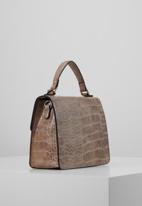 Handtas van leer met krokodillenprint in lichtbruin, gestructureerde vorm, bovenhandvat en metalen sierelementen. Gladde oppervlakte met subtiele glans.