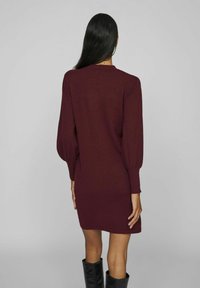 Burgundy tröja klänning med långa, puffärmar och ribbade detaljer. Mjuk textur, tajt silhuett och når till mitten av låret, ovanför knäet.