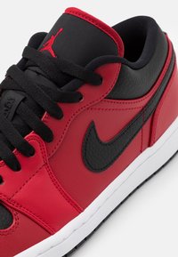 Röda lädersneakers med svarta detaljer, texturerad sidopanel, vit mellansula, svarta snören och Jumpman-logotyp på tungan.