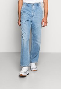 Lyseblå denimjeans med rett passform, høy midje og frynsete kanter. Kombinert med hvite sneakers med beige såle.