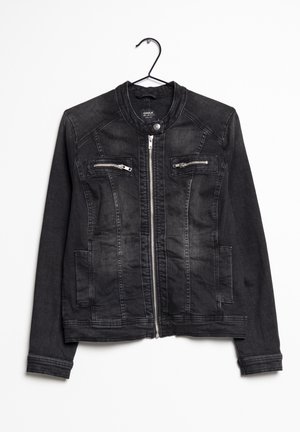 Veste en denim noire avec fermeture éclair à l'avant, deux poches poitrine zippées et manches longues, suspendue sur un cintre noir.