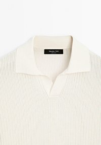 Pletený pulovr s v-výstřihem ve světlé krémové barvě, s ribovanou texturou a kontrastním límcem. Štítek zní "Massimo Dutti." Měkký, lehký materiál.