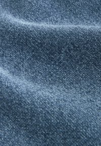 Prim-plan al unui textil albastru moale, texturat, cu o suprafață ușor ridicată și pufoasă, având pliuri delicate care creează umbre subtile.