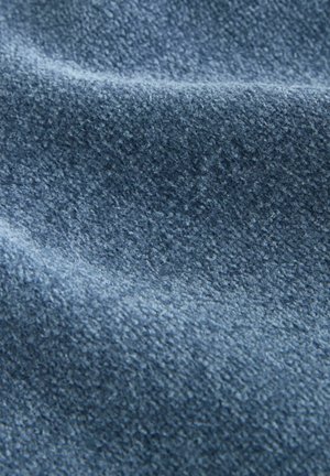 Detailný záber na mäkkú, textúrovanú modrú tkaninu s mierne zdvihnutým, chlpavým povrchom a jemnými záhybmi, ktoré vytvárajú jemné tiene.