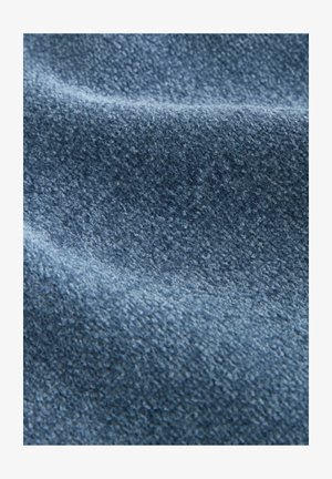 Nahaufnahme von weichem, strukturiertem blauen Stoff mit einer leicht erhöhten, flauschigen Oberfläche und sanften Falten, die subtile Schatten erzeugen.