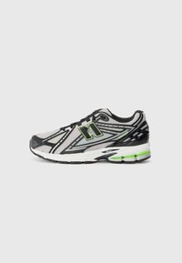 Chaussure de sport noire et grise avec tige en maille, présentant une accentuation verte et un design à motifs. Semelle rembourrée pour le soutien.