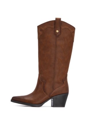 Bota de vaquero de cuero marrón con punta afilada, costuras decorativas y tacón cuadrado. Presenta una parte superior curva con una correa en bucle para facilitar el uso.