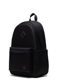 Black backpack made of durable fabric, featuring a rounded shape, large front pocket, and leather logo patch. Adjustable straps on top.