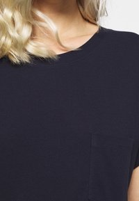 Navyblaues Baumwoll-T-Shirt mit Rundhalsausschnitt und kurzen Ärmeln, das ein kleines Taschen detail auf der linken Brust hat.