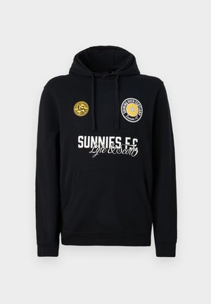 Melna kapuce ar kājām, ar baltu tekstu "SUNNIES FC" un dzelteniem izšūtiem uzšuvēm. Izgatavota no mīkstas, teksturētas auduma.