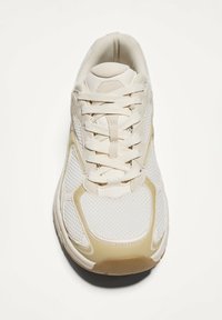 Scarpa da ginnastica bianca con tomaia in rete e materiale sintetico, collo imbottito e suola testurizzata. Presenta dettagli beige e lacci piatti.