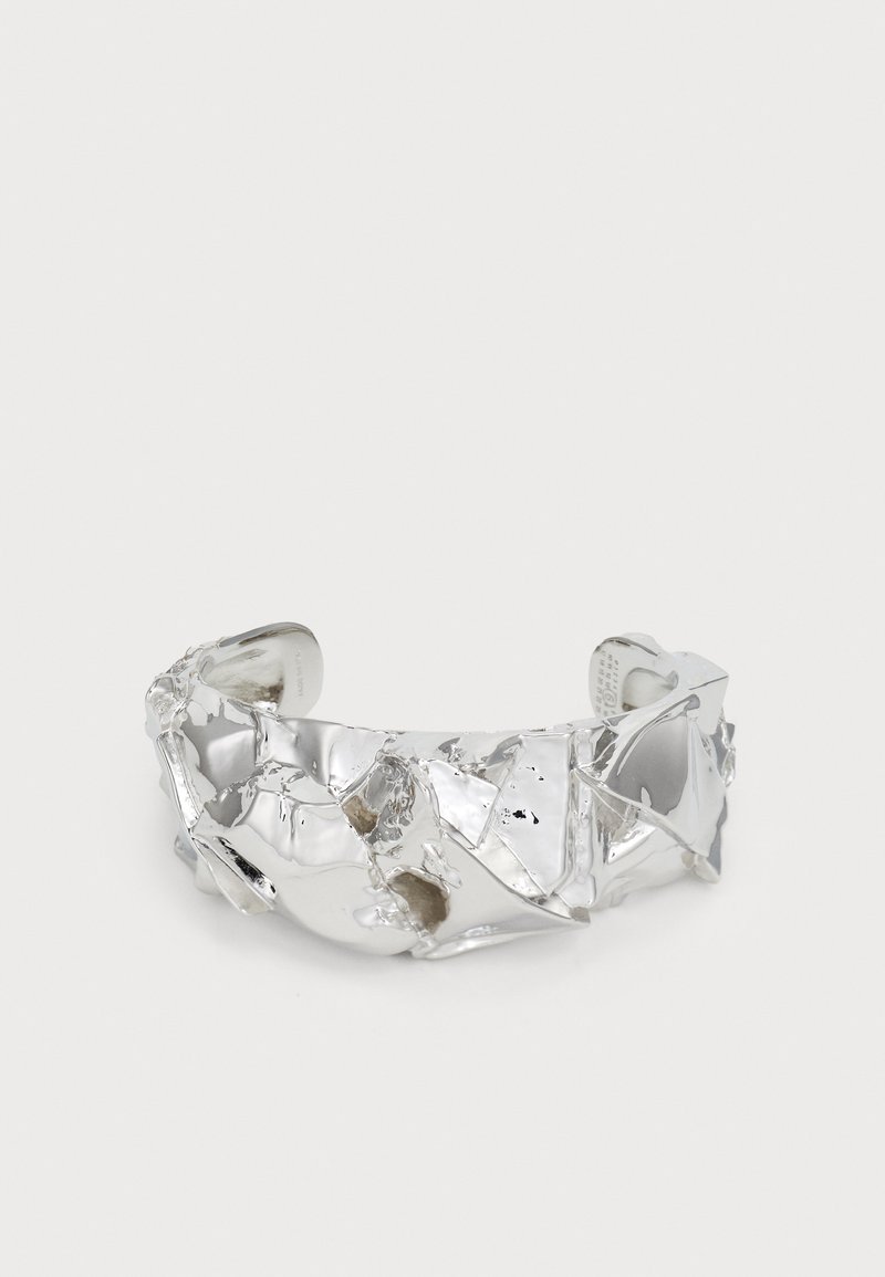 Silver cuff bracelet featuring a distorted, irregular surface with shine and texture variations. Open ends with polished finish.