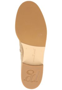 Suela de zapato de ante beige con una superficie suave, forma ligeramente redondeada y logo en relieve. Suela de goma marrón claro para tracción.