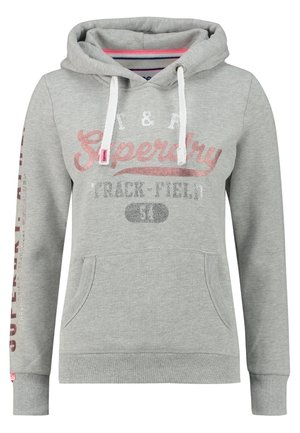 Jasnoszara bluza z kapturem z białymi sznurkami, kieszenią z przodu oraz różowo-srebrnym napisem „Superdry Track & Field” na piersi i rękawie.
