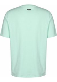 Tyrkysové tričko vyrobené z bavlny. Krátké rukávy, kulatý výstřih, na zadní části u krku je malé černé logo "PUMA". Jednoduchá, hladká textura.