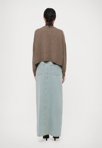 Hnedý skrátený sveter s raglánovými rukávmi skombinovaný s svetlomodrou džínsovou maxi sukňou so zadnými vreckami a rovnou siluetou.